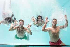 Two couples swimming underwater in swimming pool