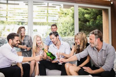 Man pouring champagne in glasses for friends