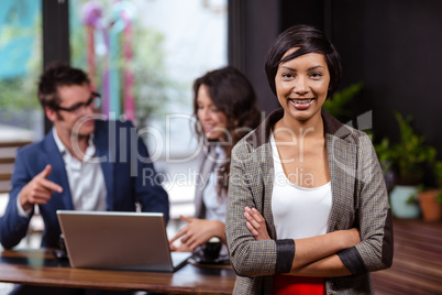 Woman with arms crossed and people using laptop