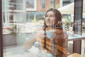 Woman looking through window with coffee