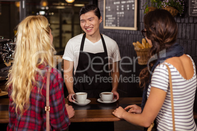 Smiling waiter serving a coffee to customers