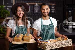 Smiling baristas holding bread and desserts