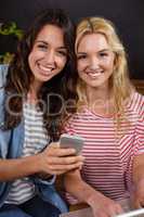Smiling friends watching a smartphone together