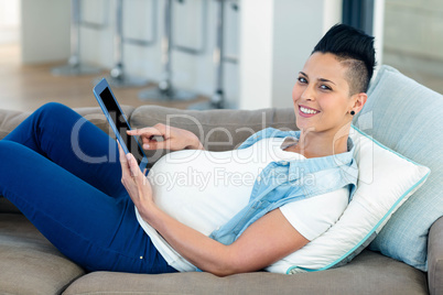 Portrait of pregnant woman relaxing on sofa with her digital tab