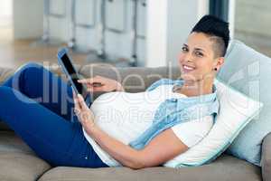 Portrait of pregnant woman relaxing on sofa with her digital tab