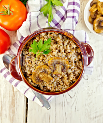 Buckwheat with champignons in clay bowl on board top