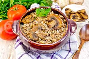 Buckwheat with champignons in clay bowl on napkin