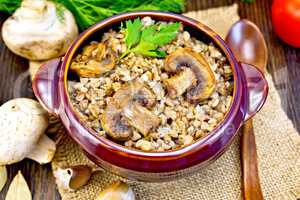 Buckwheat with champignons in clay bowl on table