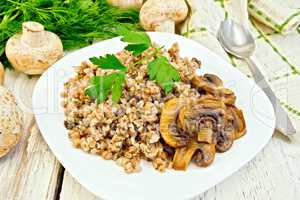 Buckwheat with champignons in plate on light board