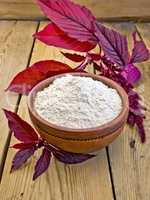 Flour amaranth in clay bowl on board with purple flower