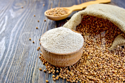 Flour buckwheat in bowl and spoon with cereals on board