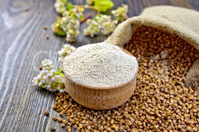 Flour buckwheat in bowl with cereals and flower on board