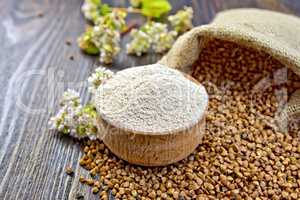 Flour buckwheat in bowl with cereals and flower on board