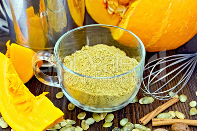 Flour pumpkin in glass cup with seeds and sieve on board