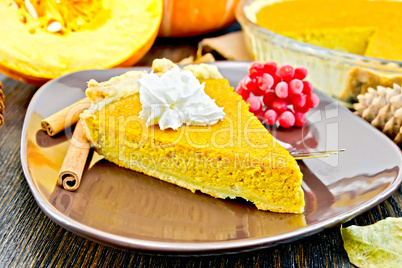 Pie pumpkin in brown plate with cream on dark board