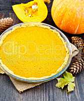 Pie pumpkin in pan on dark board