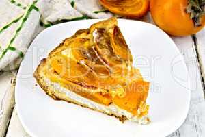 Pie with curd and persimmons in plate on light board