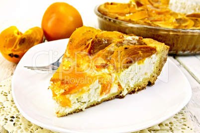 Pie with curd and persimmons in white plate on napkin silicone