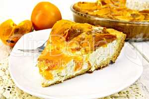 Pie with curd and persimmons in white plate on napkin silicone