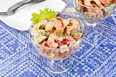 Salad with shrimp and tomatoes in glass on blue tablecloth