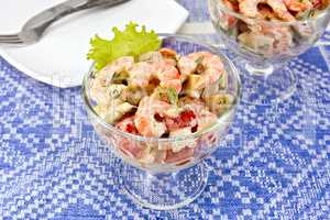 Salad with shrimp and tomatoes in glass on blue tablecloth