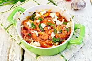 Shrimp and tomatoes with feta in green pan on board
