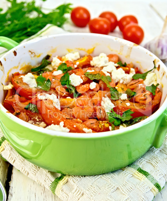 Shrimp and tomatoes with feta in green pan on napkin