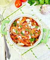 Shrimp and tomatoes with feta in pan on napkin top