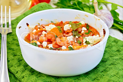 Shrimp and tomatoes with feta in white bowl on board