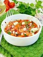 Shrimp and tomatoes with feta in white bowl on green napkin