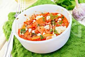 Shrimp and tomatoes with feta in white bowl on light board