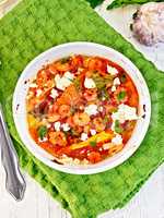 Shrimp and tomatoes with feta in white bowl on napkin top