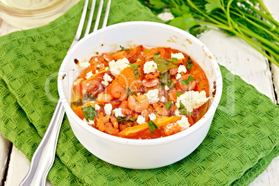 Shrimp and tomatoes with feta in white bowl on napkin