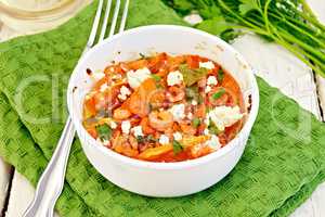 Shrimp and tomatoes with feta in white bowl on napkin