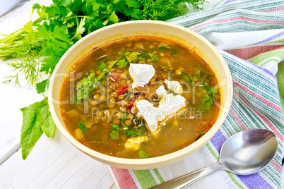 Soup lentil with spinach and cheese in yellow bowl on board