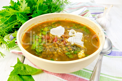 Soup lentil with spinach and feta in yellow bowl on board