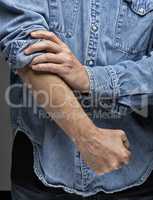 Man in denim shirt rolling up his sleeves
