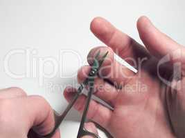 nail scissors in the process of cutting nails on a man's hand