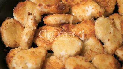 Batter-fried chicken meat nuggets is cooked on pan