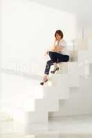 Adult businesswoman sitting on steps and looking down
