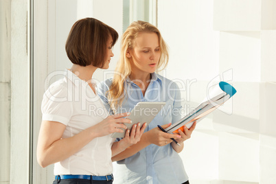 Two colleagues talking while looking at notebook