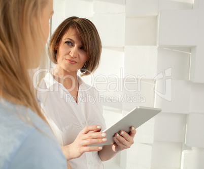 Portrait of brunette woman with tablet looking at her colleague