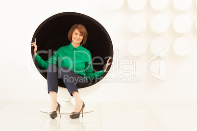 Elegant woman sitting on spherical chair