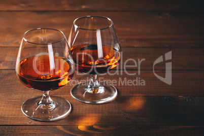 Two glasses of cognac on the wooden table.