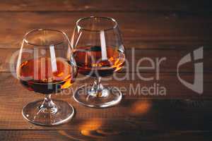 Two glasses of cognac on the wooden table.