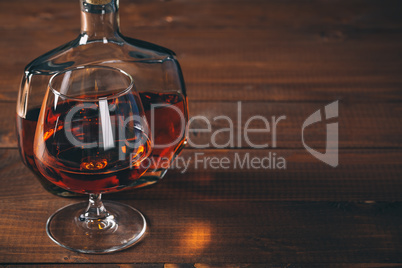 Glasses of cognac and bottle on the wooden table.