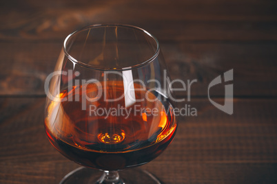 Glass of cognac on the wooden table.