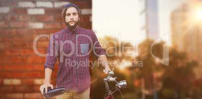 Composite image of hipster with bicycle against fence