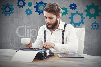 Composite image of hipster holding coffee working on typewriter