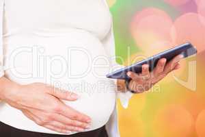 Composite image of midsection of pregnant woman using tablet com